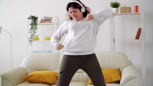 Woman with Headphones Energetically Dancing at Home