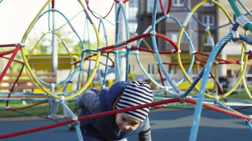 Caucasian Child Climbing through Net Structure on Playground