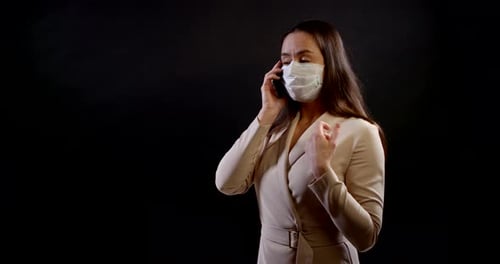 Woman in Mask Using Phone on Black Background