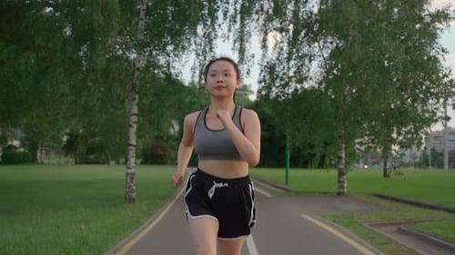 Asian Young Beautiful Woman Running for Health in the Evening Sunset on Street in Public Park