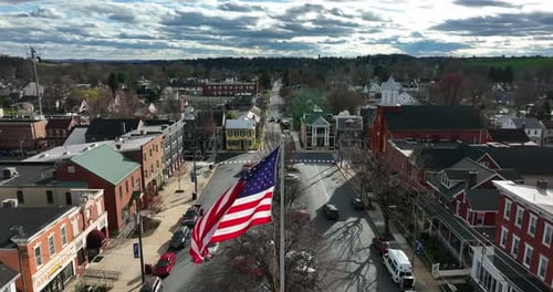 American town on bright sunny day. Bright sunlight transitions to cloudy. Tattered USA and Pennsylva