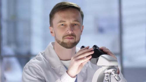 Smiling Scientist Looks Through Microscope in Lab