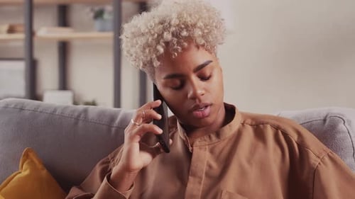 Jovem mulher de pele escura curtindo uma conversa no celular na sala de estar