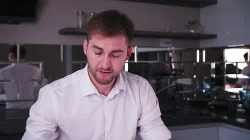 junger Mann arbeitet an einem Laptop und trinkt Kaffee