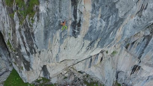 Aerial drone view of a man rock climbing up a mountain.