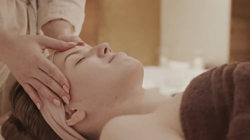Woman Relaxing During Facial Massage at a Spa