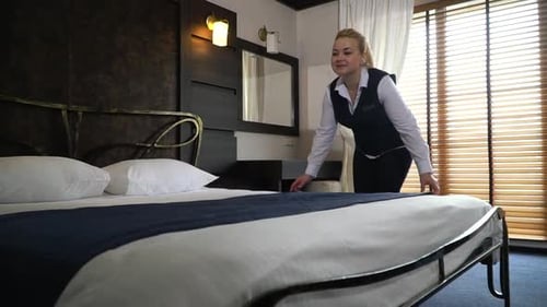 Smiling Administrator Corrects Bedclothes in the Modern Room of Hotel. Slow Motion