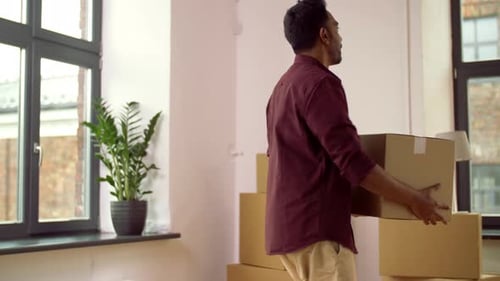Young Man Carrying Box Into Apartment