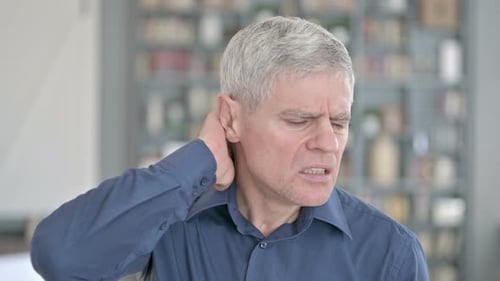 Mature Man Rubbing Stiff Sore Neck in Office