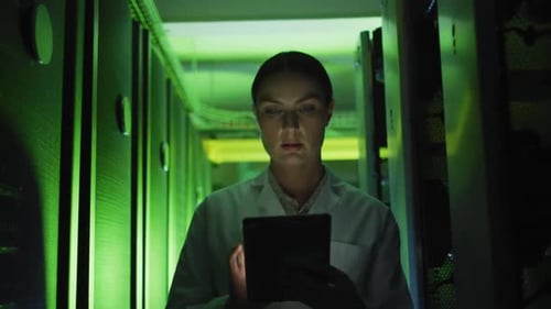 Woman in Server Room Types on Tablet