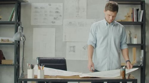 Architect Inspecting Blueprints in Bright Office Environment