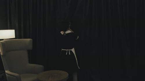 Housekeeper Closing Black Curtains in Hotel Room