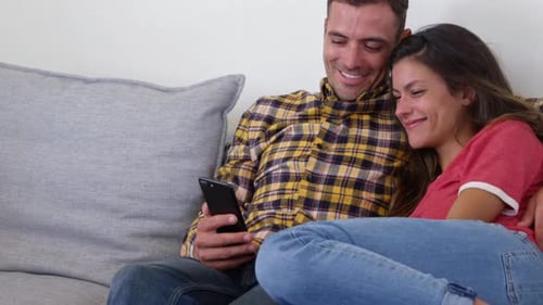 Smiling Couple Relaxing Together Looking at a Smartphone