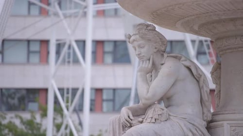 Una estatua femenina blanca y una rueda giratoria