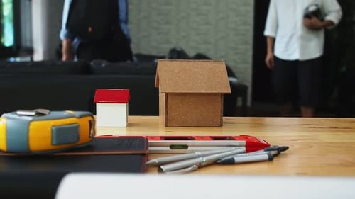 Close up of living house model on desk with architect or real estate agent background with pan left.