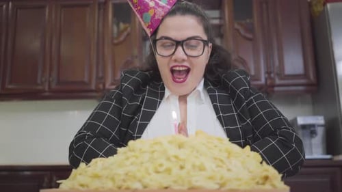 Portrait Cute Fat Happy Girl in a Festive Cap and Stylish Glasses Sitting at the Table in the