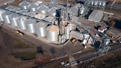 Ein Lastwagen voller Getreide fährt an einem sonnigen Tag in der Nähe großer Metallsilos des Getreideaufzugs