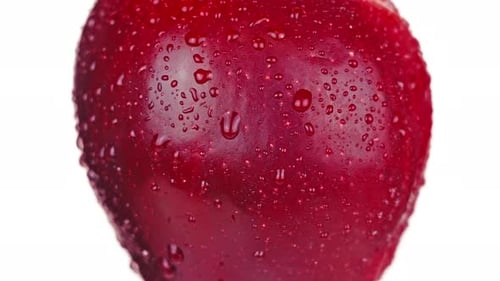 Saftiger roter Apfel mit Wassertropfen dreht sich auf Weiß nach links