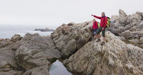 Couple Hiking on Rocky Coastline by Ocean
