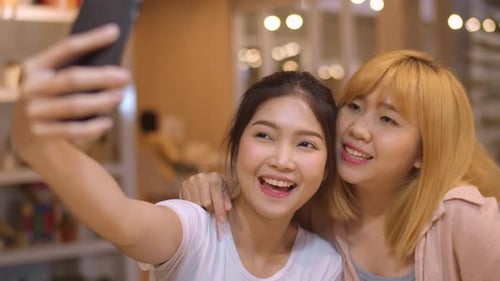 young Asia friend clicking selfie using mobile phone at a coffee shop.