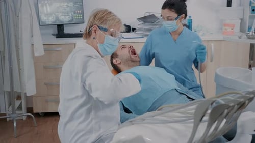 Dentist Examining Patient with Assistant in Clinic