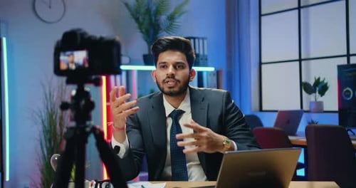 Un homme d'affaires enregistre une vidéo pour un public sur Internet tout en expliquant un graphique dans une salle de travail moderne