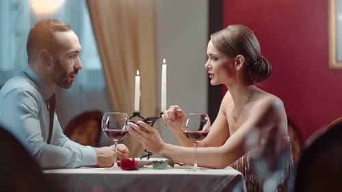 Male and Female Discussing Using Phone at Romance Meeting in Restaurant