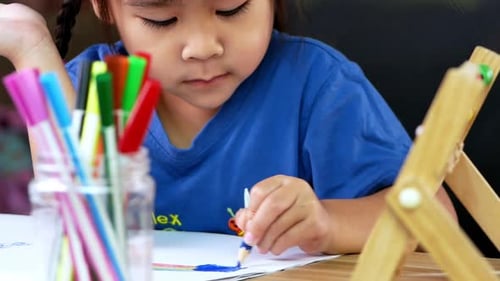 Child Drawing with Markers at Table Indoors