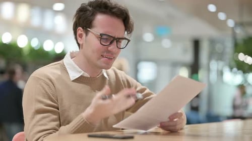 Man Reviews Documents with Concern in Office Setting