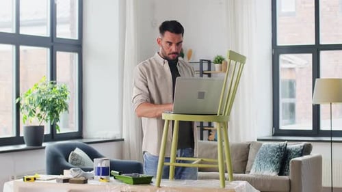 Man Works at Laptop Perched on Painted Chair