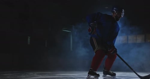 Man Hockey Player with a Puck on the Ice in Hockey Form Leaves with a Stick