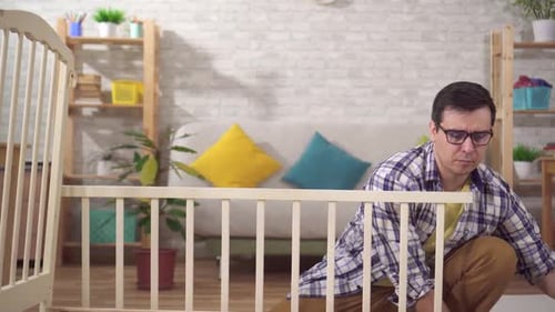 Portrait Positive Young Man Future Father Collects a Bed in the Bedroom
