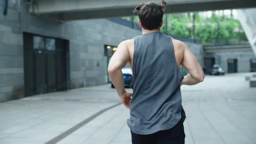Fit Man Running Outdoor in Slow Motion. Back View of Athlete Man Training Run