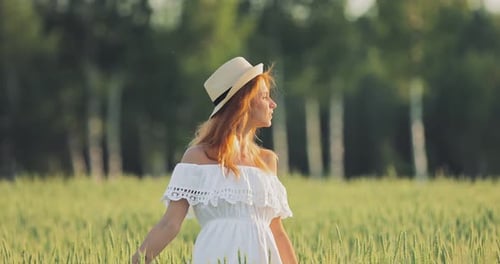 Beautiful Young Woman with a Hat is Walking Across the Field She is Happy
