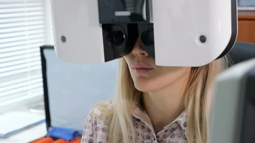 Young Woman Looking at Refractometer Eye Test Machine in Ophthalmology