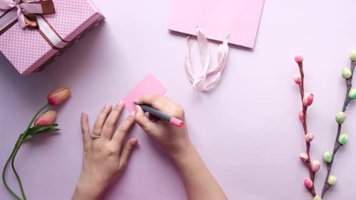 Hands Writing 'MOM' on Card for Mother's Day