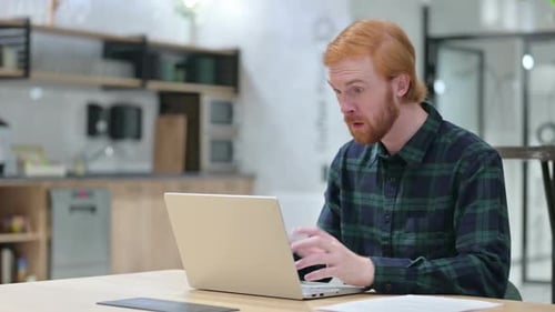Young Man Celebrating Success with Laptop Indoors
