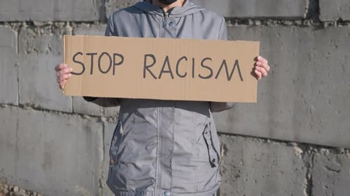 Person Holds Stop Racism Sign at Protest