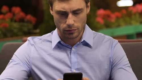 Businessman sitting in restaurant and looking at mobile phone, checking mail