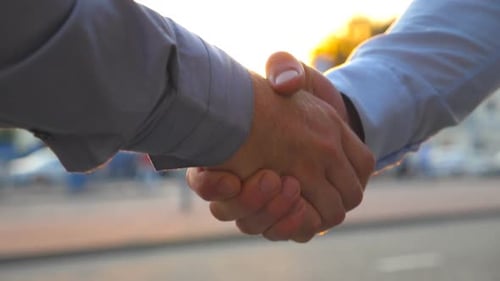 Two Successful Businessmen Greeting Each Other Against the Background of Cars Parking. Young