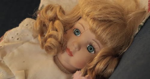 Langsam in eine Vintage-Porzellanpuppe mit blondem lockigem Haar und blauen Augen drücken