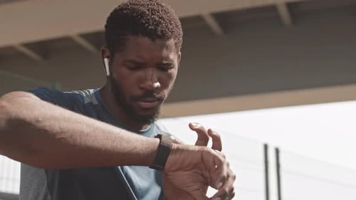 Man Checks Smartwatch After Workout in City