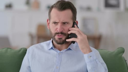 Frustrated Man Arguing on Mobile Phone Indoors