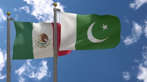 Mexico and Pakistan Flags Waving Under Blue Sky