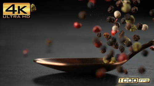 Colorful Peppercorns Falling from Spoon on Slate Surface