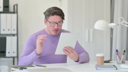 Man Reacts to Bad News on Tablet in Office