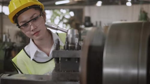 mechanical engineer or operation woman wear uniform goggles safety working on workshop metal lathe