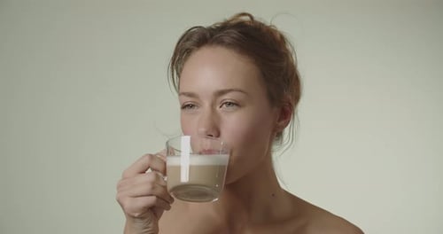 Woman Drinking Foamy Latte from Clear Mug