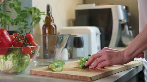 Adult Chopping Cucumber on a Cutting Board