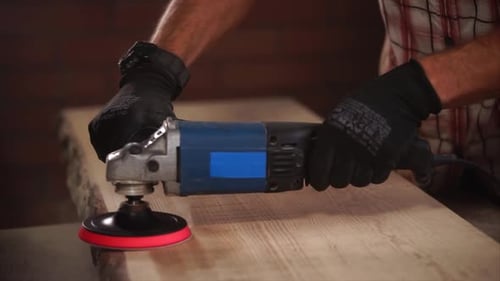 Man Sands Wooden Board with a Power Tool